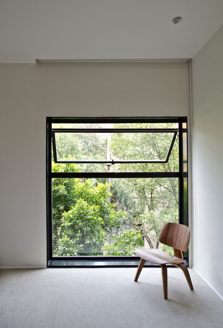 a chair sitting in front of a window on top of a carpeted floor next to a white wall