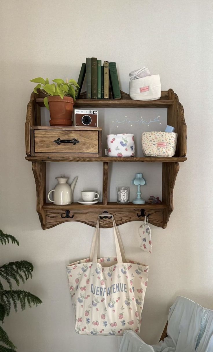 a wooden shelf with two shelves holding books and a tote bag hanging from it