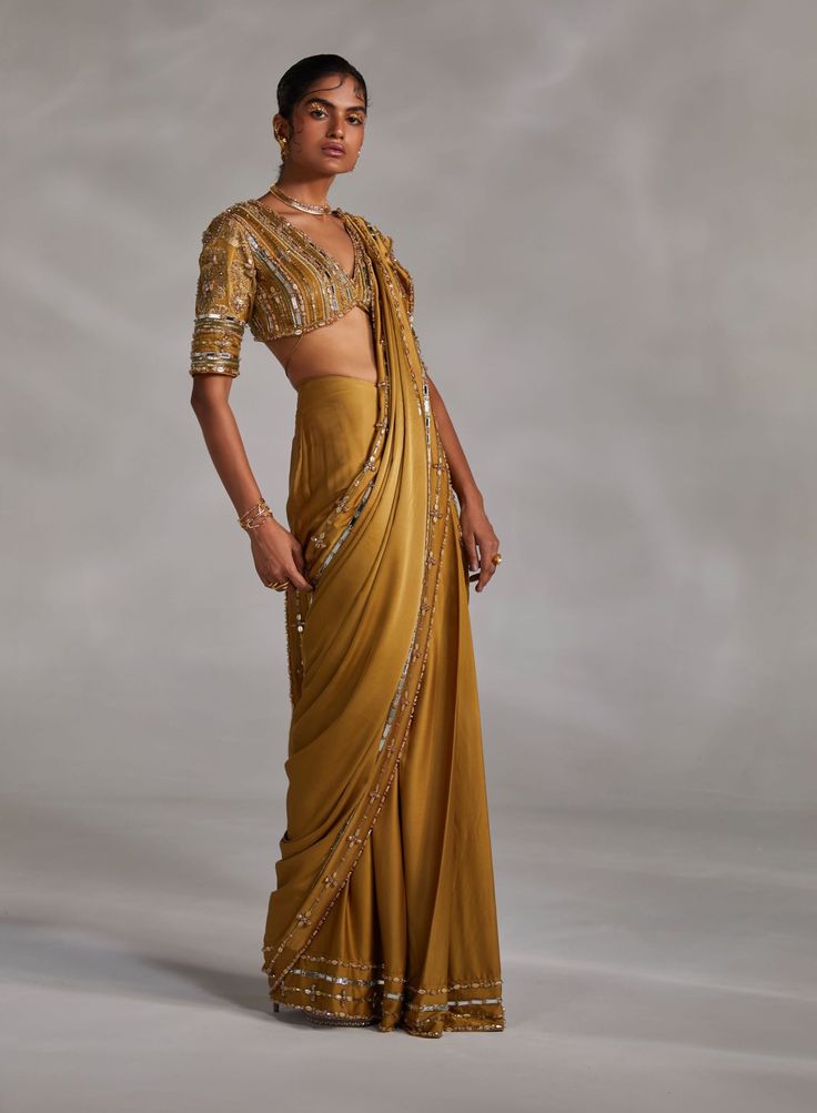 Editor's Note Featuring a hand-embellished blouse with drawstring closure and solid pre-drape sari with hand-embellishment details on border Color: Olive green Fabric: Silk satin Fit type: Blouse: fitted Neckline: V-neck Components: Sari and blouse Occasion: Haldi mehndi and Wedding Guest Care: Dry Clean Only About the Designer The crux and essence of the label, Divya Aggarwal, is to challenge and revamp the face of ordinary traditional wear while being customer oriented. Driven by the values of Party Wear Pre-draped Saree With Gota Work For Reception, Gold Silk Pre-draped Saree With Mirror Work, Designer Party Wear Pre-draped Saree With Gota Work, Party Wear Pre-draped Saree With Gota Work, Silk Pre-draped Saree With Mirror Work For Party, Pre-draped Saree With Gota Work For Reception, Gold Pre-draped Saree With Mirror Work For Evening, Party Silk Saree With Gota Work, Party Wear Pre-draped Saree For Reception With Gota Work