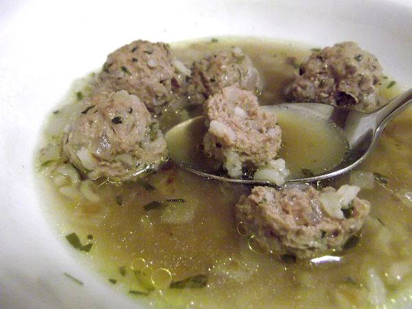 a spoon filled with soup and meatballs