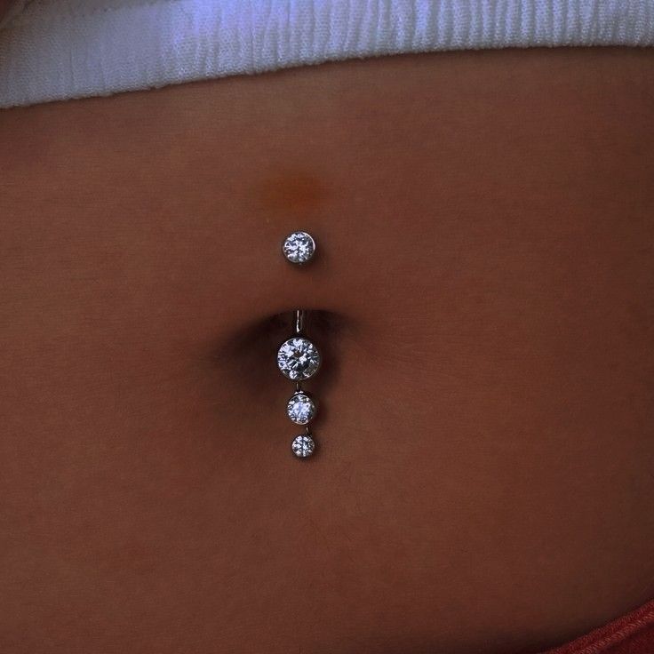 a woman's belly with three diamond studs attached to the back of her stomach