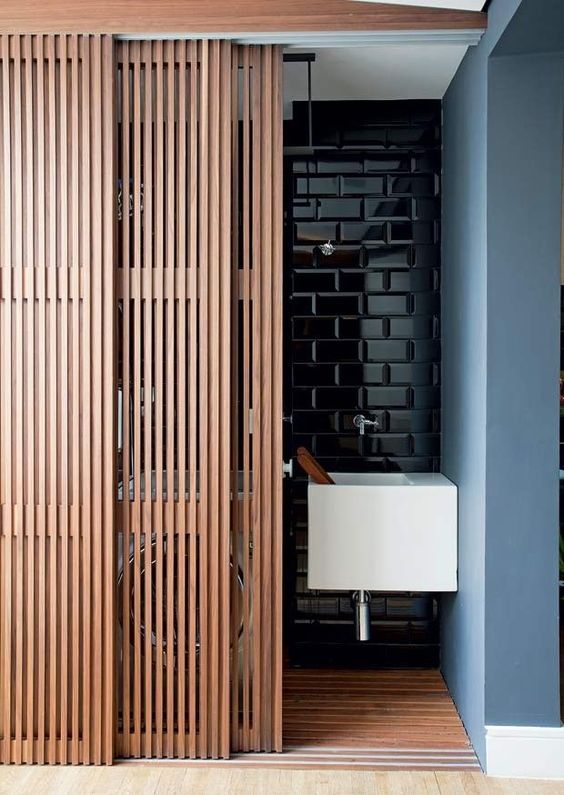 an open door leading to a bathroom with wood slats on the walls and floor