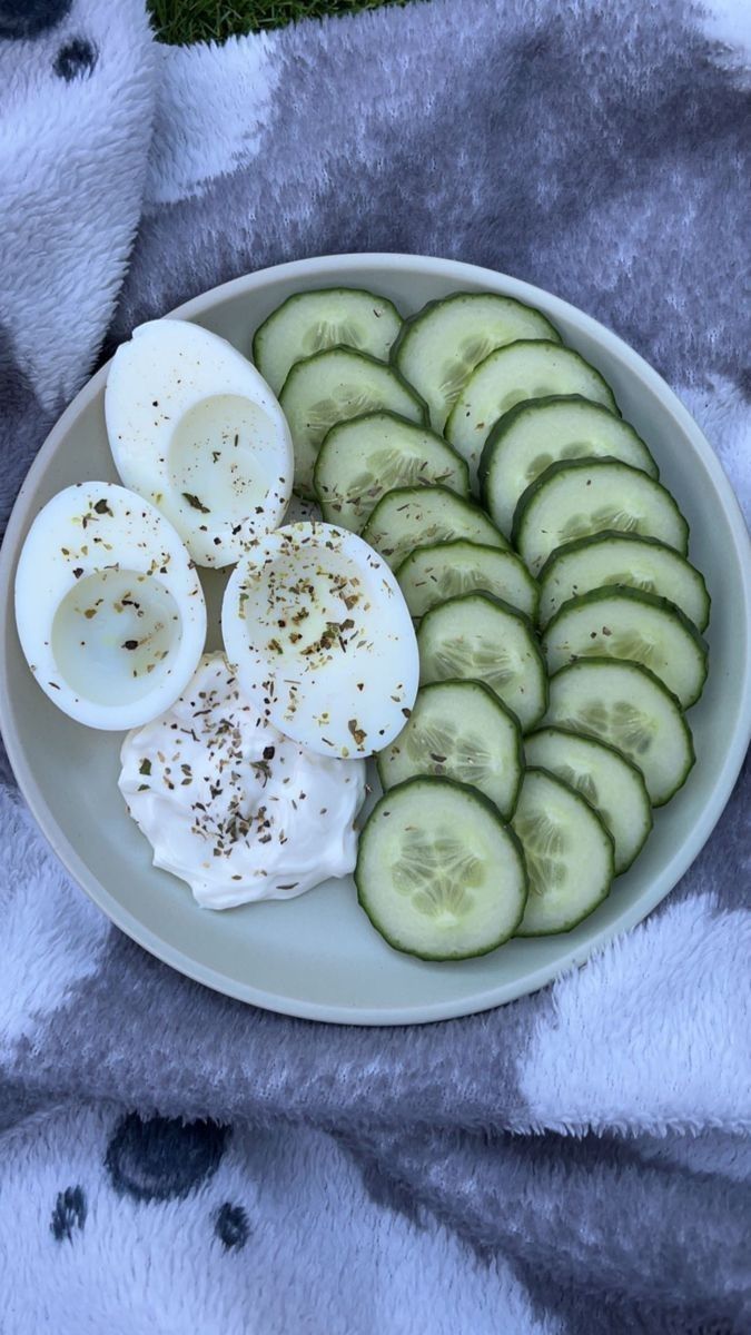 cucumber slices and hard boiled eggs on a white plate with a gray towel