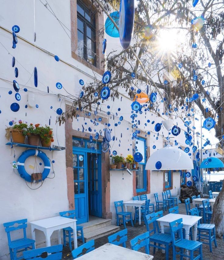 an outdoor cafe with blue chairs and tables on the side of the street in front of a white building