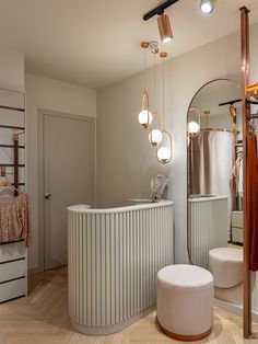 a bathroom with an oval mirror and stool in the corner, next to a white tub