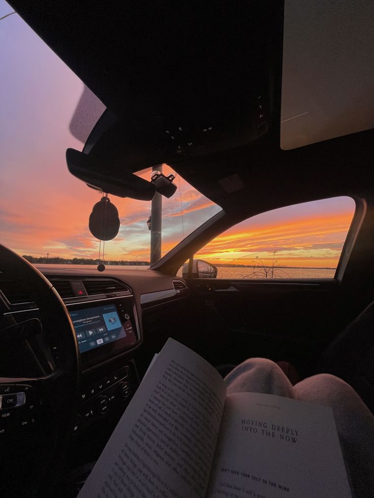 the sun is setting in the distance as seen from inside a car with an open book