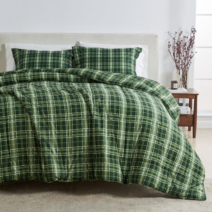 a bed with green plaid comforter and pillows