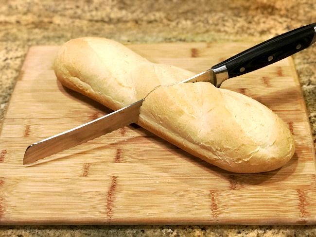 two loaves of bread on a cutting board with a knife