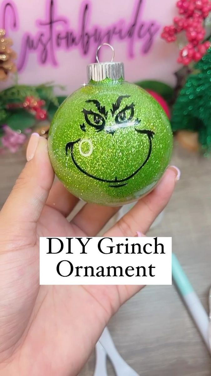 a hand holding a green ornament with a smiley face drawn on it