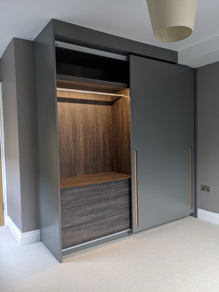 an empty room with some closets and drawers on the wall, in front of a light fixture