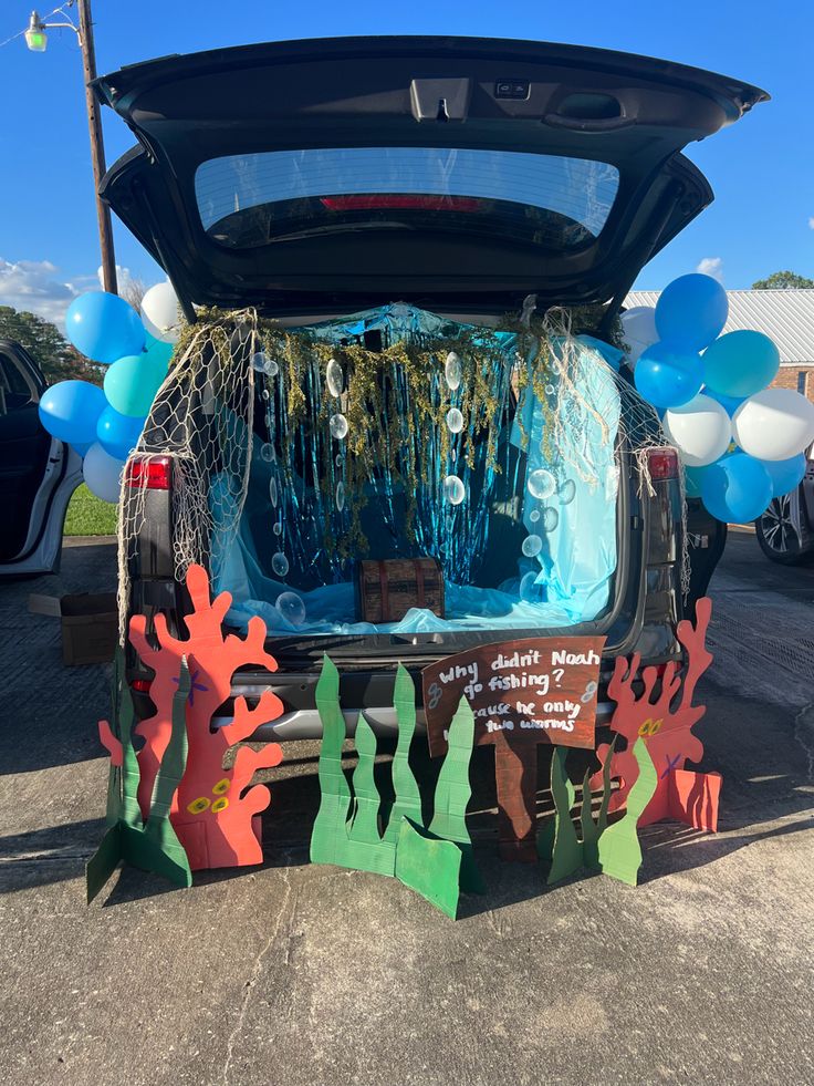 the trunk of a car decorated with underseam and mermaid tail finks for an ocean themed birthday party