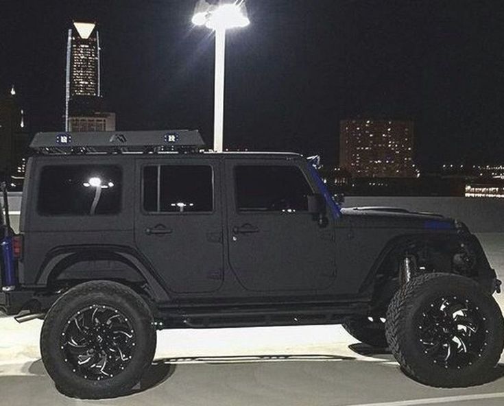 a black jeep parked in a parking lot at night