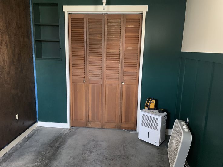 an air conditioner sitting in the corner of a room with green walls and wooden shutters