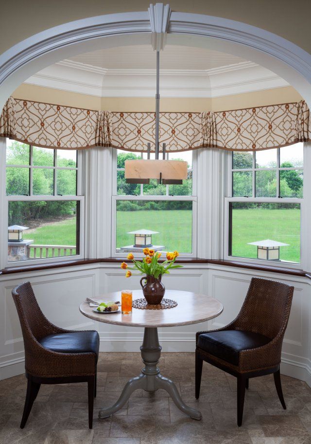 a table with two chairs and a vase on it in the middle of a room