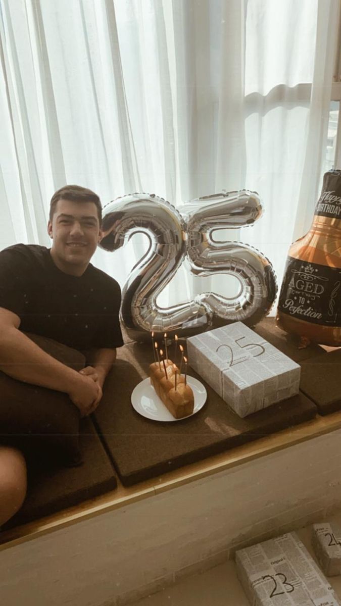 a man sitting in front of a cake with the number twenty five candles on it