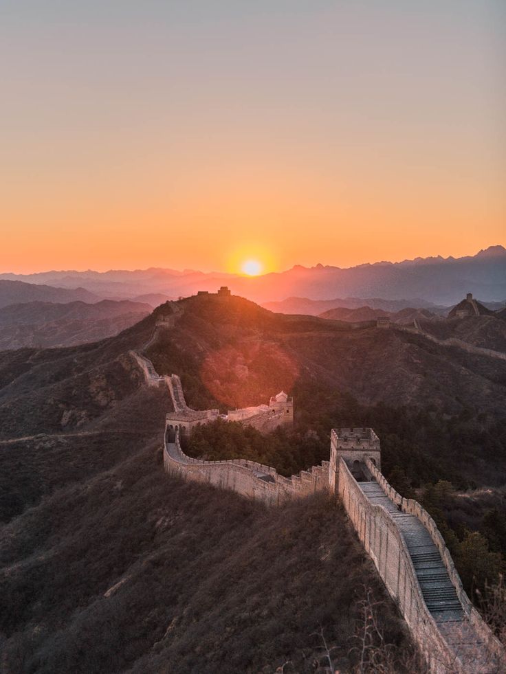 the sun setting over the great wall of china