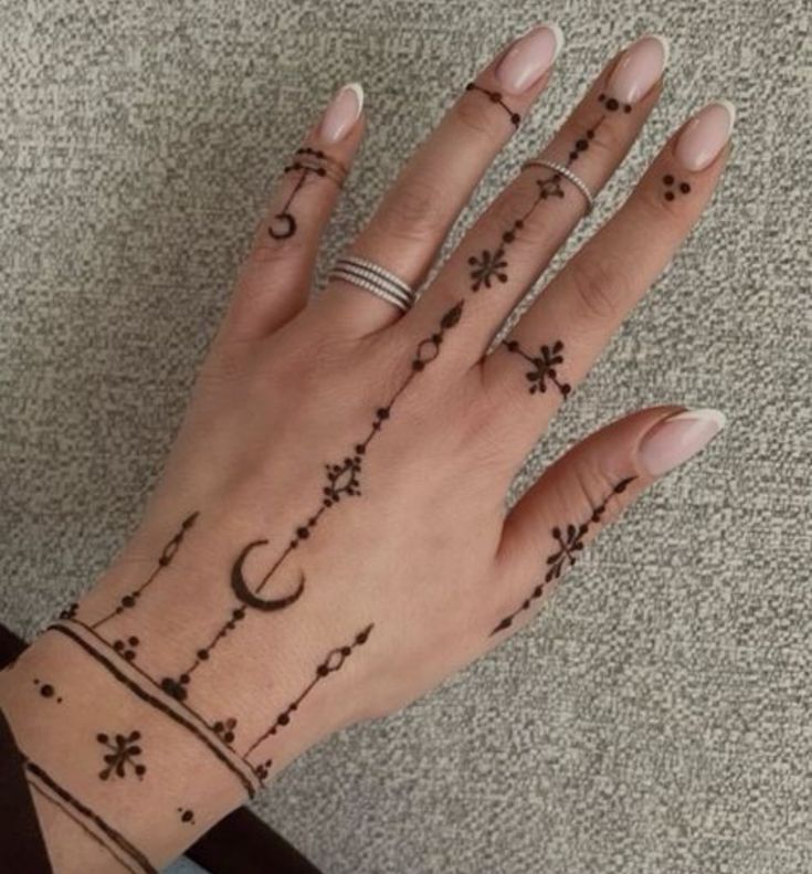 a woman's hand with tattoos on it and two rings in the middle of her fingers