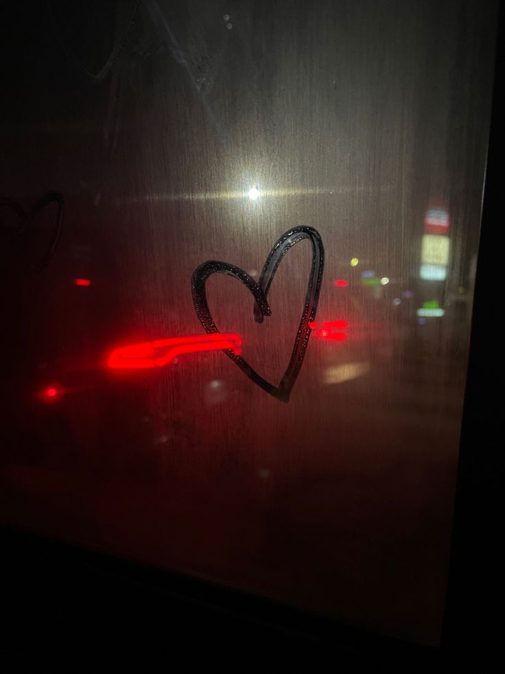 a heart is drawn on the side of a car door with red light behind it