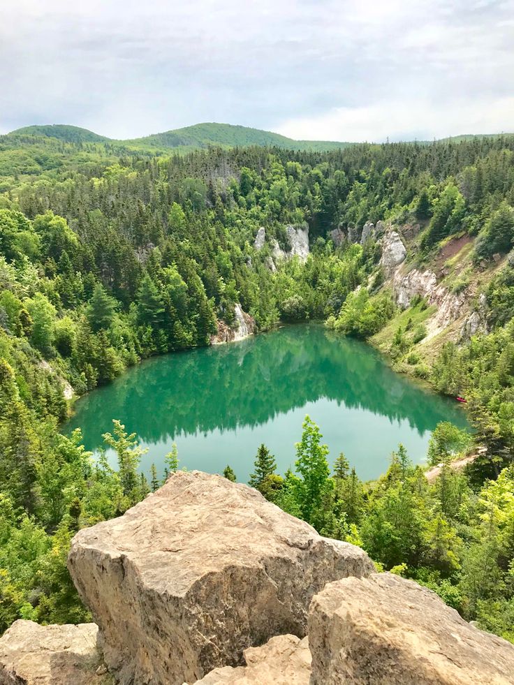 a lake surrounded by trees and rocks in the middle of a mountain range with blue water