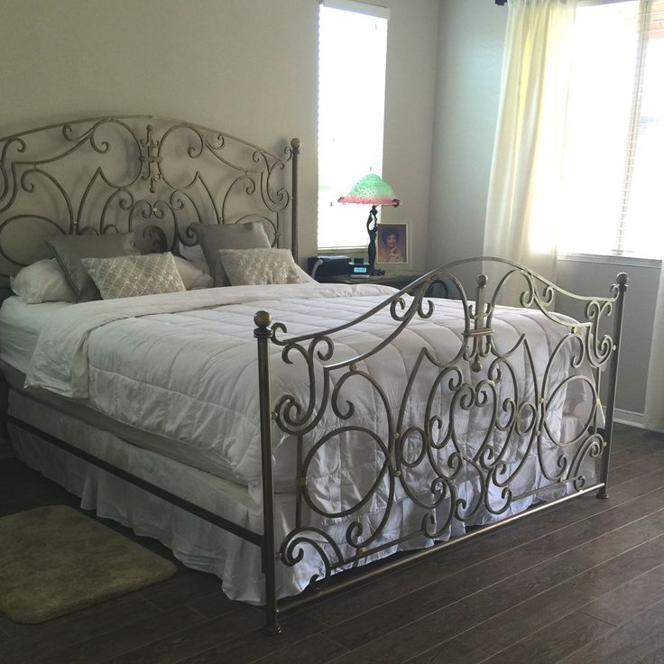 a bed sitting in the middle of a bedroom next to a window with white curtains