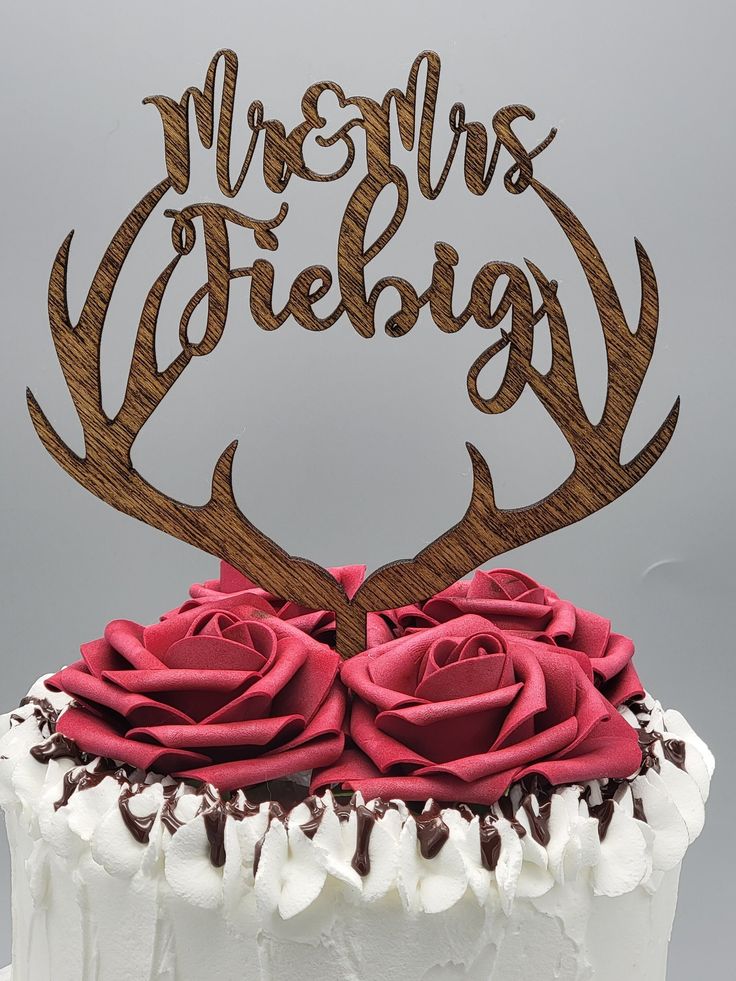 a white cake topped with a red rose and antler's head on top