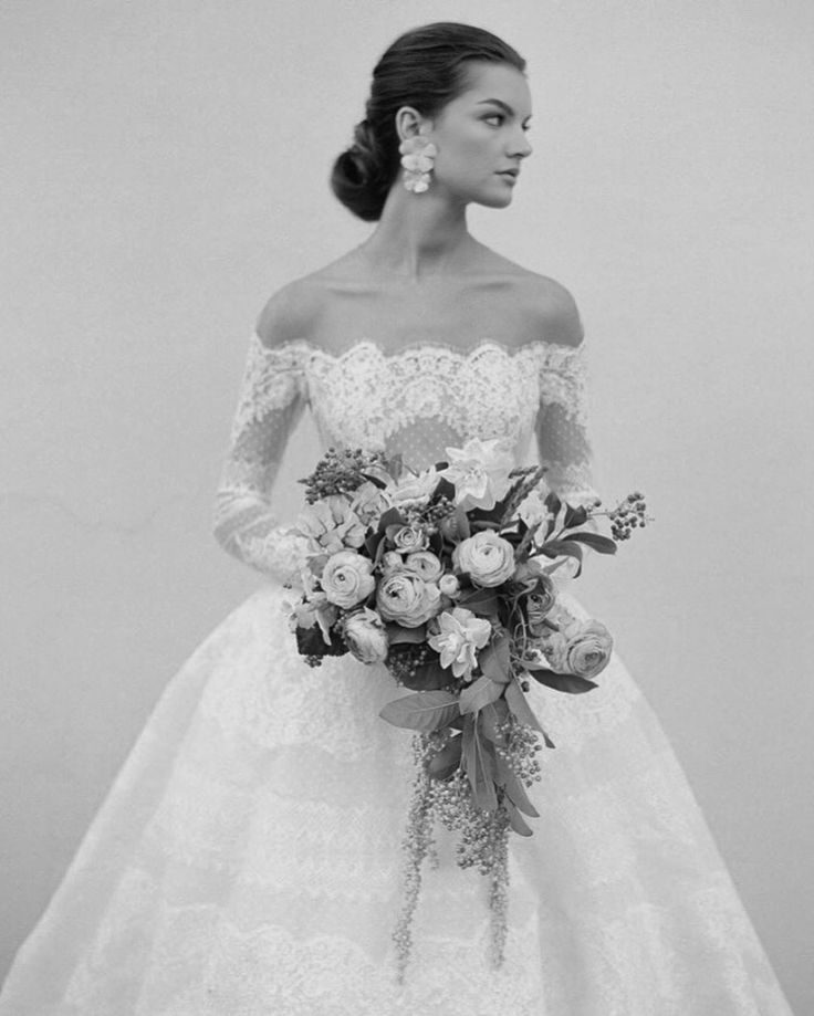 a woman in a wedding dress holding a bouquet and looking off to the side with her hand on her hip