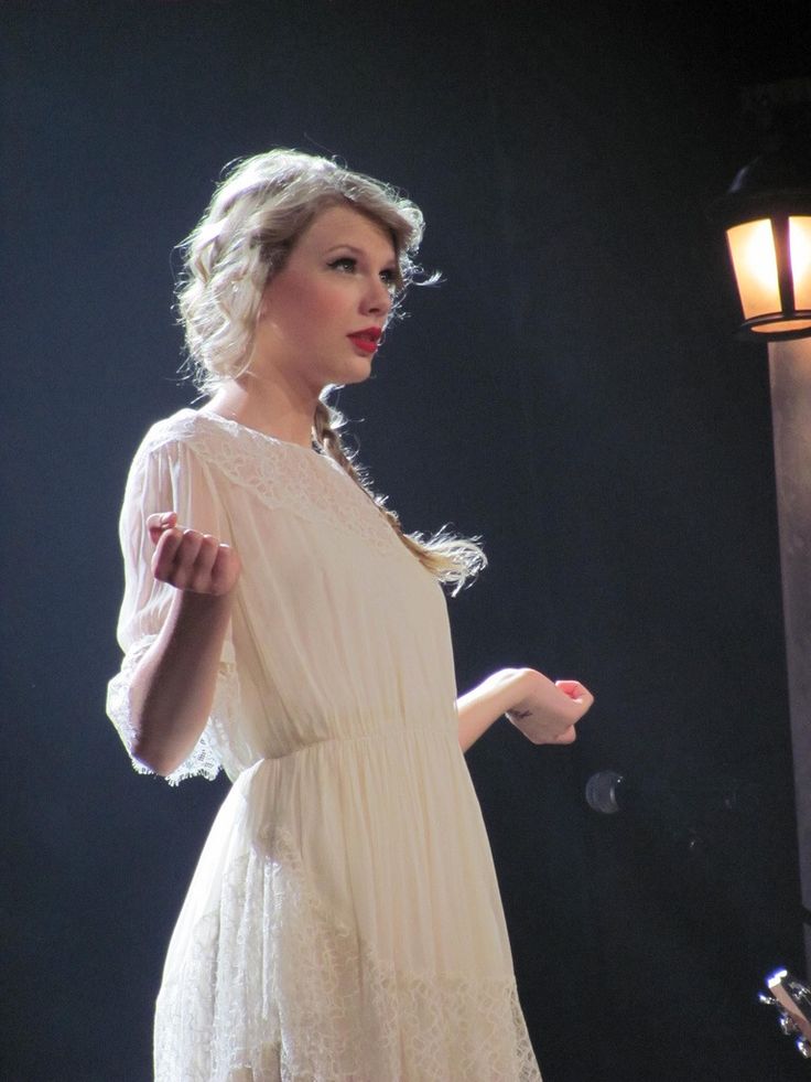 a woman in a white dress is holding her hand out and looking off to the side