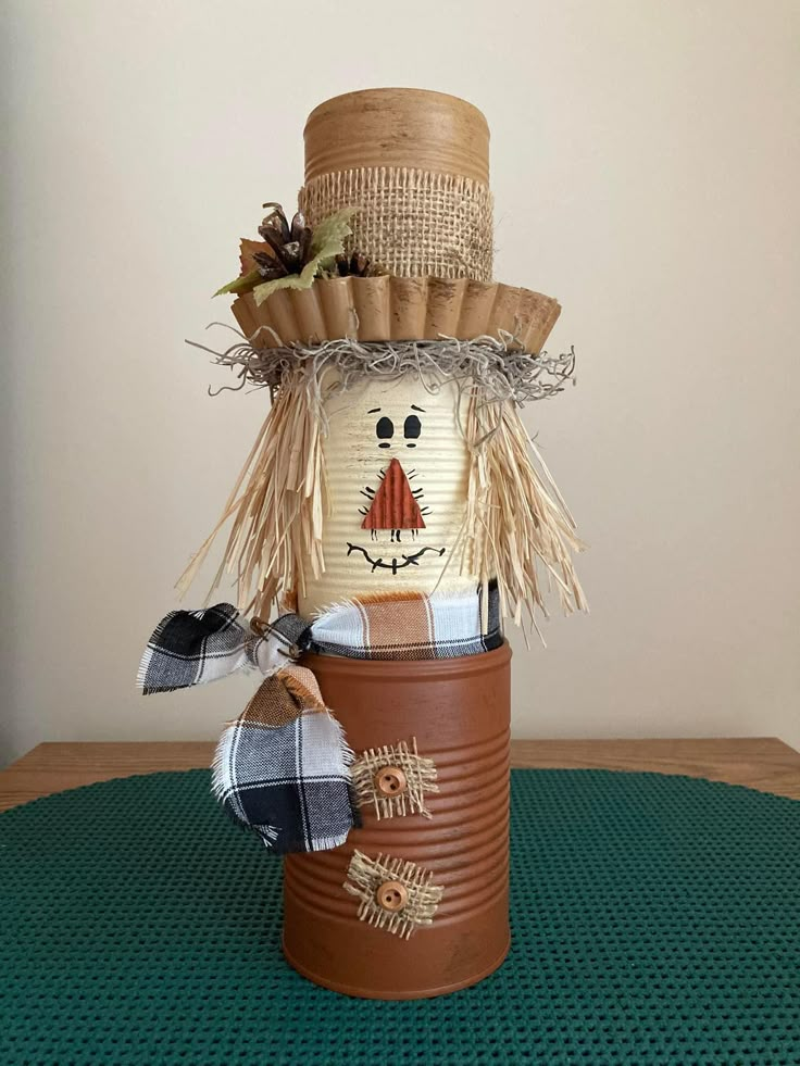 a tin can with a scarecrow on it sitting on a green tableclothed surface