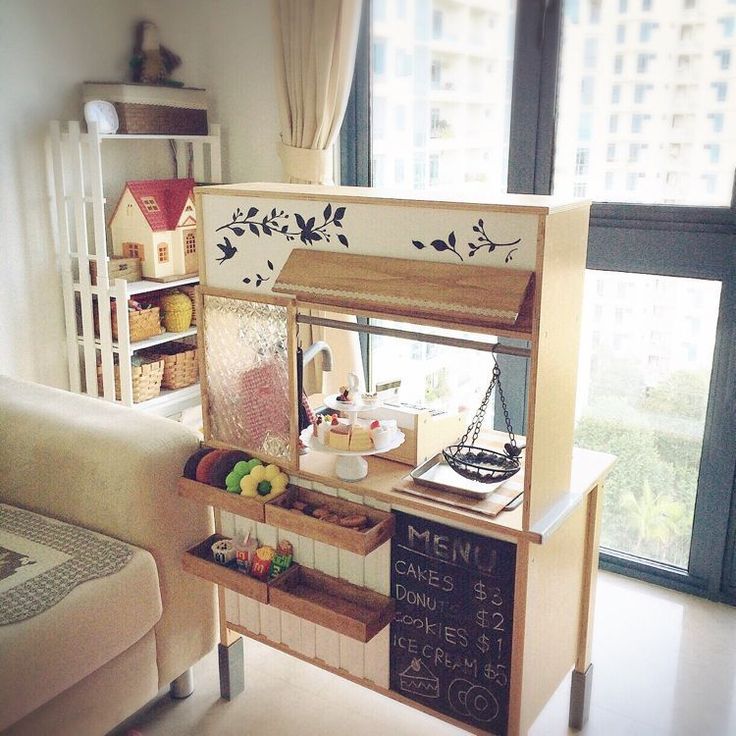 a doll house is set up in the corner of a living room with a large window