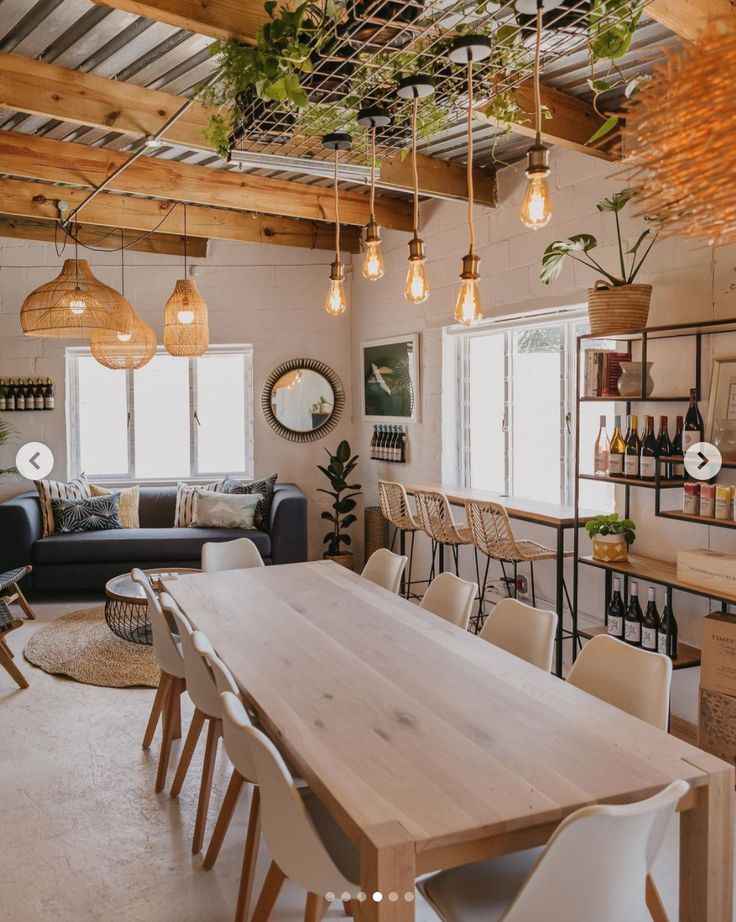 a dining room table surrounded by chairs and hanging lights in a living room with exposed wood beams