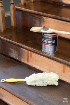 a can of paint sitting on the steps next to a brush