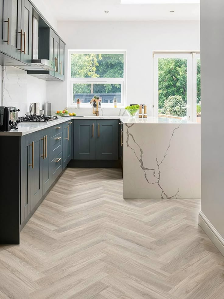 a kitchen with wood flooring and grey cabinets in the center, along with a marble counter top island