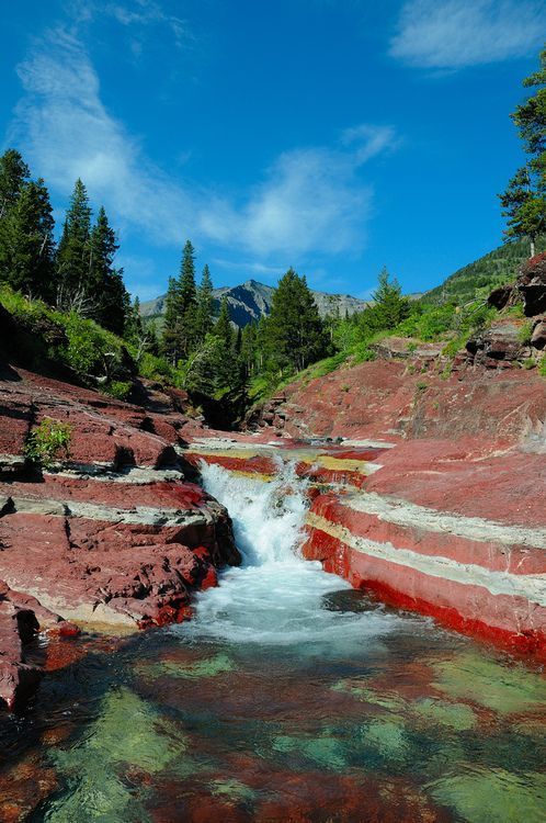 a stream running between two red rocks in the mountains