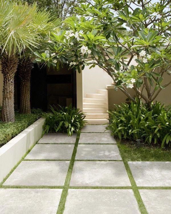 the walkway is lined with plants and trees in front of an entrance to a house