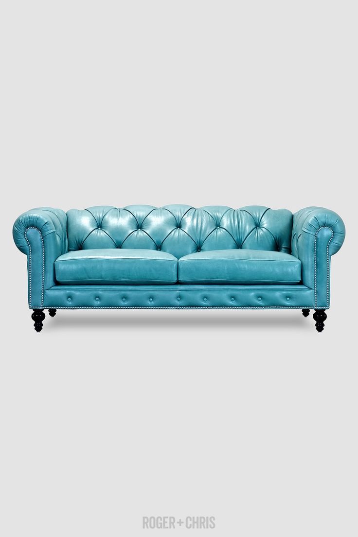 a blue leather couch with black legs and buttons on the back, against a gray background