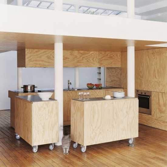 a kitchen with wood floors and white walls is shown in this image, there are two wooden island tops on wheels