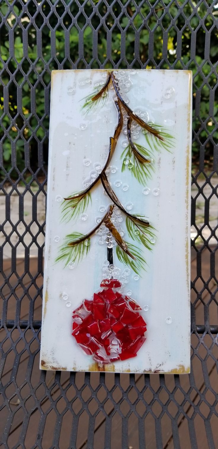 a piece of art that looks like a tree with leaves on it and red flowers