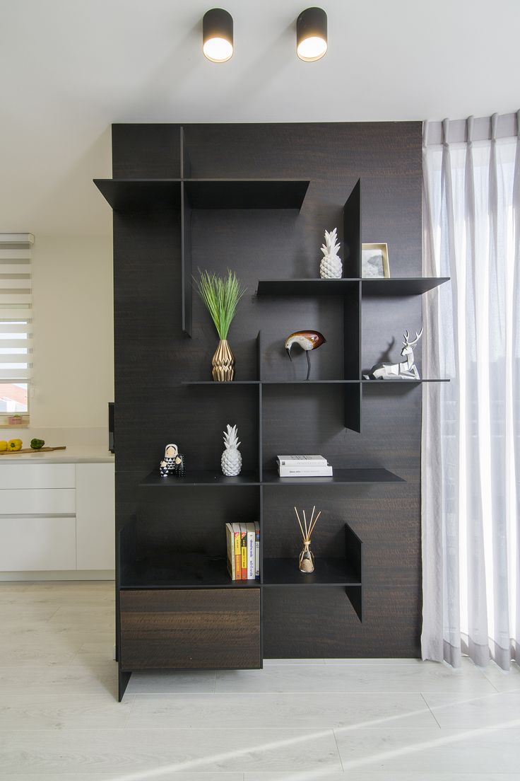 a black shelf with books and vases on it