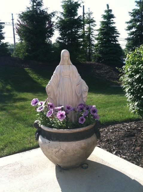 a statue in a pot filled with purple flowers