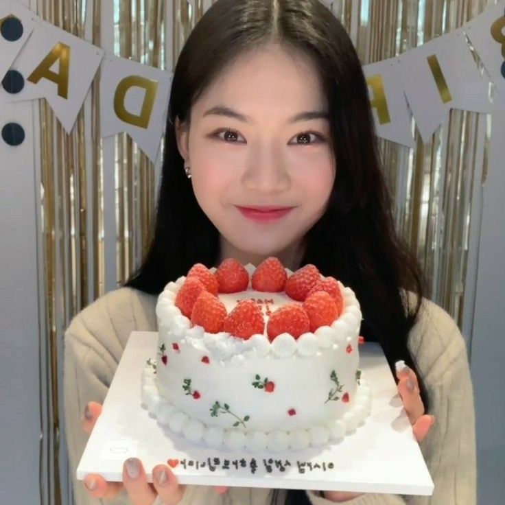 a woman holding a white cake with strawberries on it