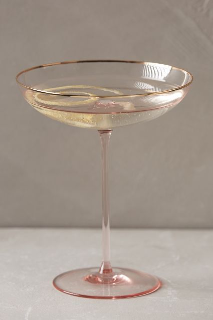 a glass filled with white wine sitting on top of a table next to a wall