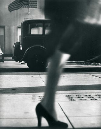 black and white photograph of woman walking down the street