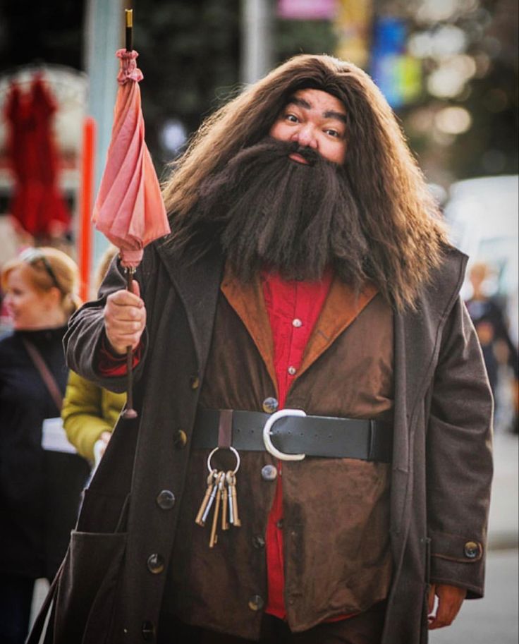 a man with long hair and beard holding an umbrella in his hand while walking down the street