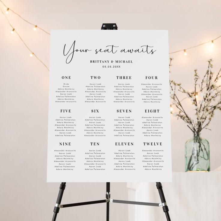 a table plan sitting on top of a easel next to a vase filled with flowers