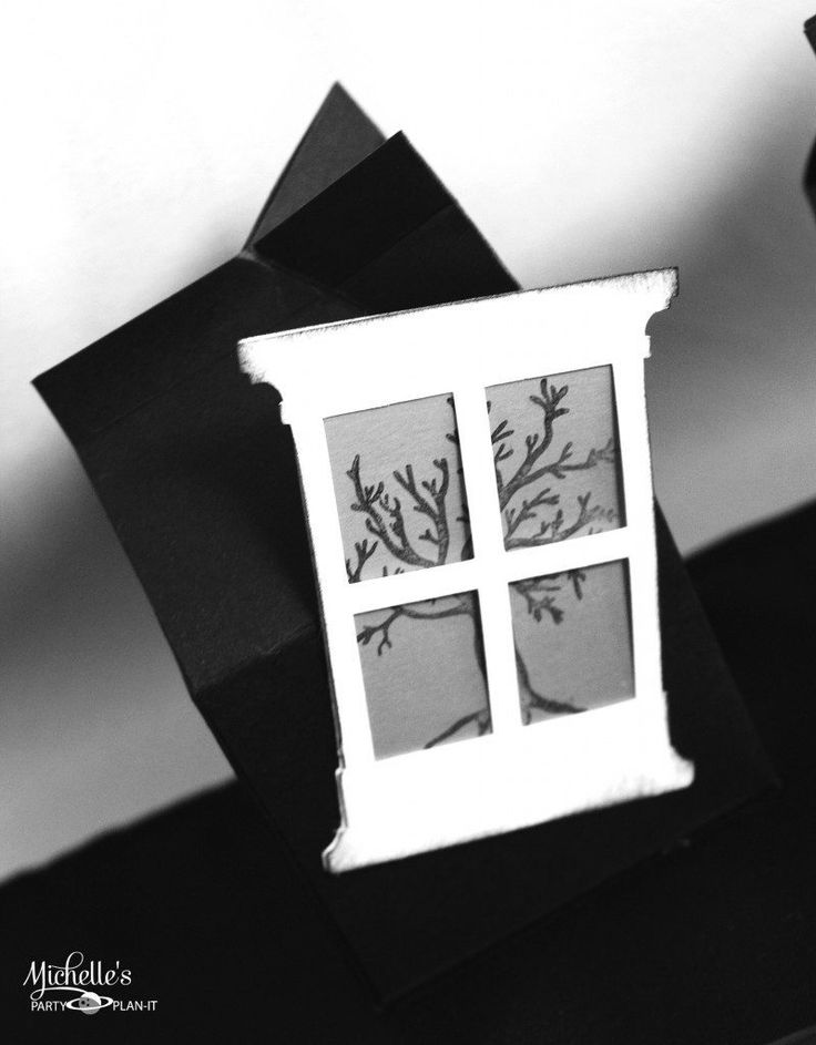 a black and white photo of a house made out of paper with trees in the window