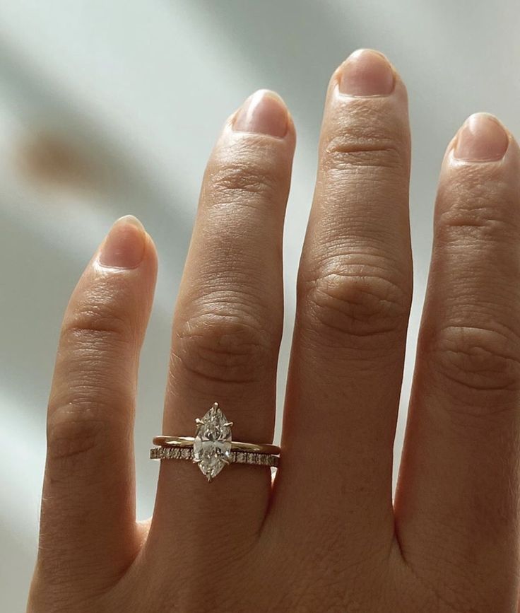 a woman's hand with a diamond ring on top of her finger and an engagement band