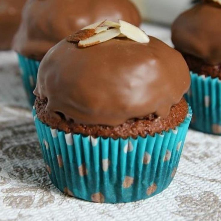 three cupcakes with chocolate frosting and nuts on top