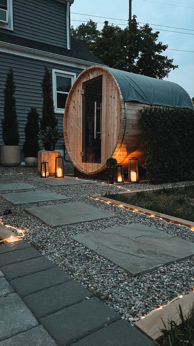 a wooden barrel sitting in the middle of a yard next to some lights and plants