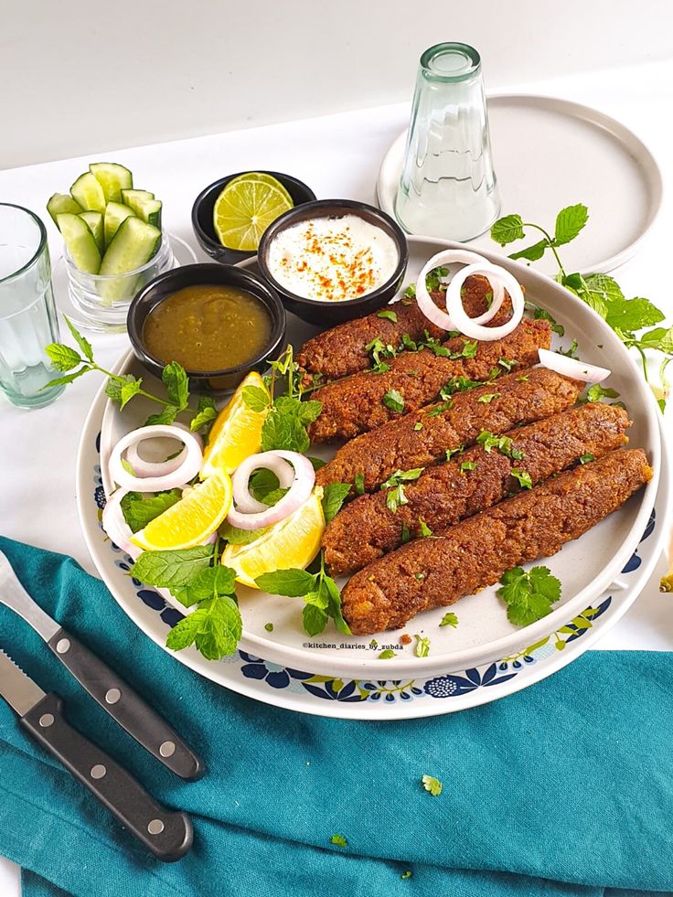 a plate with meat, sauces and vegetables on it next to utensils