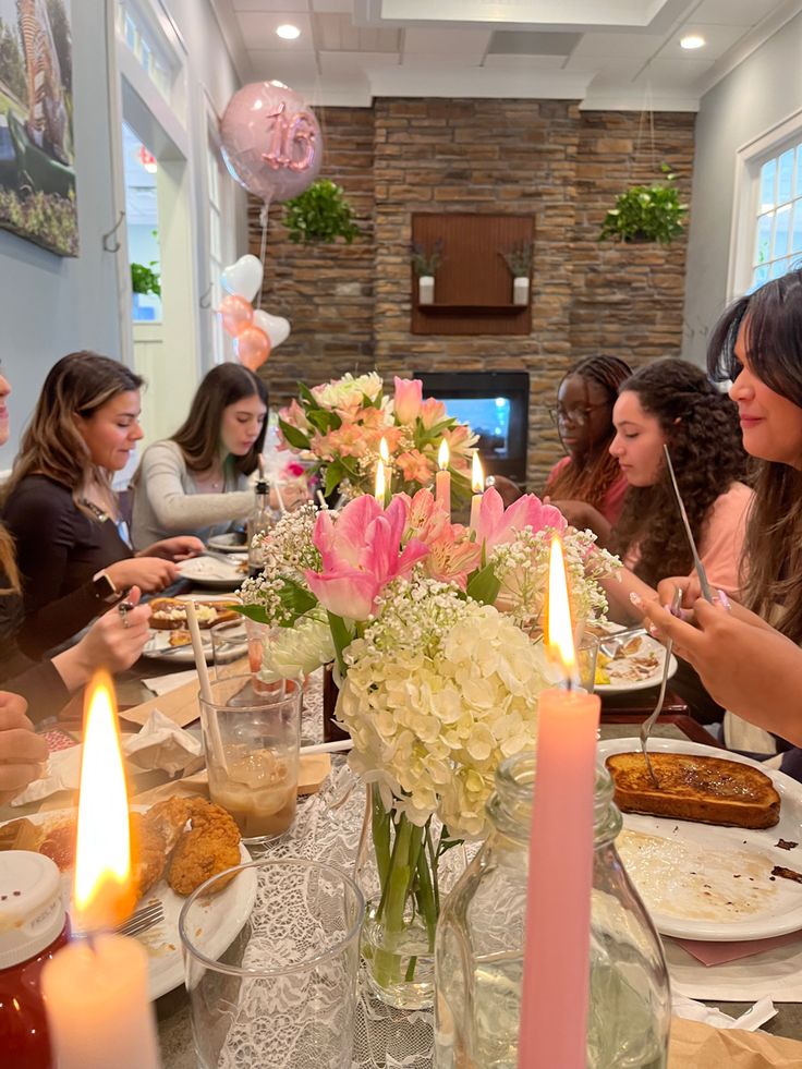 a group of people sitting around a table with food and candles in front of them